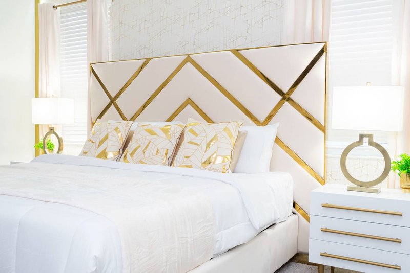 Second master suite with king bed and gold geometric headboard